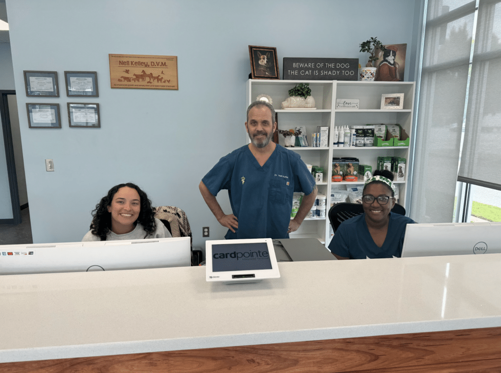 Three people standing behind a reception desk in a veterinary clinic.