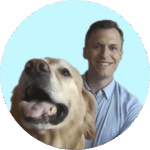 Man smiling behind a happy golden retriever in a close-up portrait.
