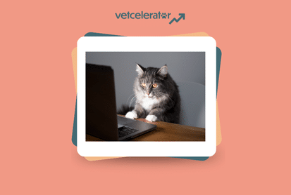 A cat sitting behind a laptop on a wooden table.