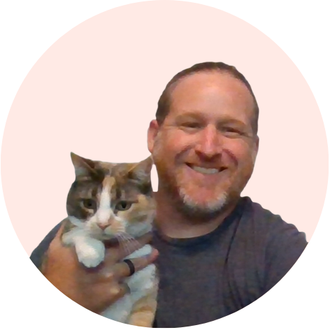 Smiling man holding a calico cat.
